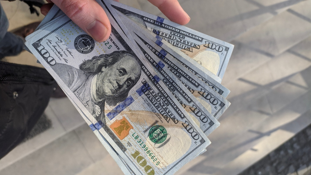 An individual showing 100-dollar notes